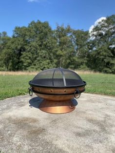 a fire pit sitting on top of a cement slab in the middle of a field