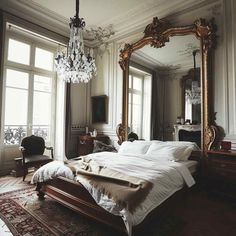 a bedroom with a large bed, chandelier and mirror in the middle of it