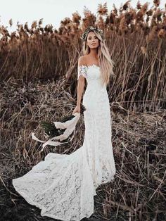 a woman wearing a white dress standing in tall grass