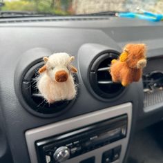 two stuffed animals hanging from the dash board of a car