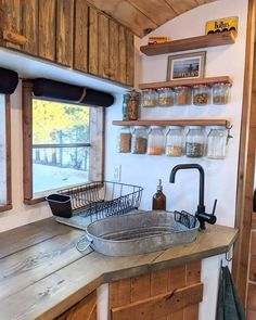 a kitchen with a sink, window and shelves on the wall above it that are made out of wood planks