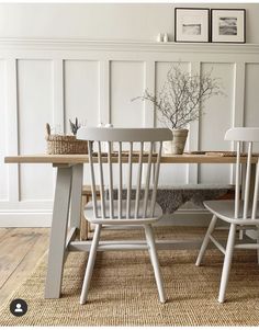 two white chairs sitting at a table in front of a wall