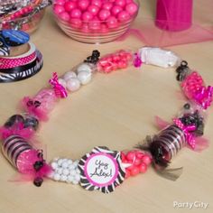 a table topped with lots of pink and white candies next to a bowl of candy