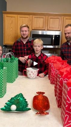 a group of people sitting around a kitchen table with christmas presents on the counter top