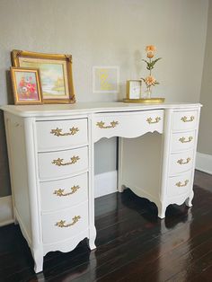 a white desk with gold trimmings on top and drawers in front of it