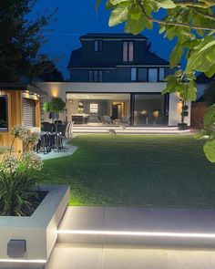 a large house that is lit up at night with lights on the grass and lawn