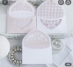 three cards with white lace and pearls on them, one has a heart in the middle