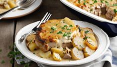 two white plates topped with chicken and potatoes covered in gravy next to a casserole dish