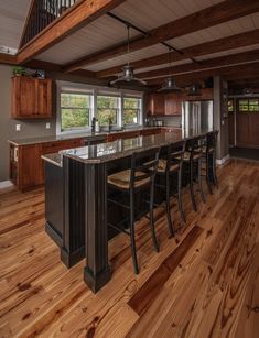 a large kitchen with an island in the middle and wooden flooring on the other side