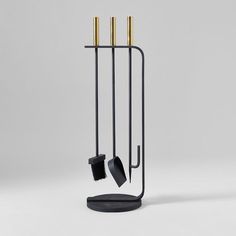 a black and gold coat rack with two brooms on it's sides, next to a brush