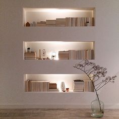 a vase filled with flowers sitting on top of a wooden floor next to bookshelves