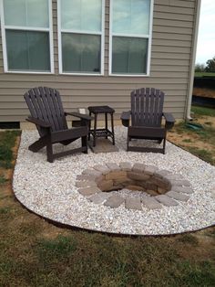 an outdoor fire pit surrounded by lawn chairs and gravel in front of a gray house