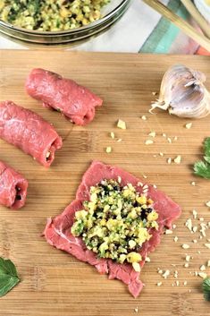 raw meats and vegetables on a cutting board next to a bowl of seasoning