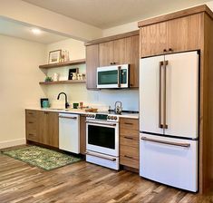 a kitchen with wooden cabinets and white appliances in it's center island, along with hardwood flooring