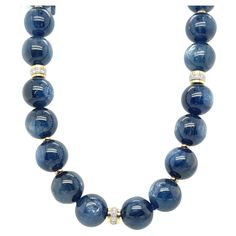 This blue kyanite gemstone beaded necklace is breathtakingly luminescent with its gorgeous silvery white sheen and luxurious satin-like appearance! The 14mm kyanite beads display varying shades of rich, medium blue and have been hand-strung and knotted with royal blue silk thread. The 18k white gold diamond-studded rondelles and 18k yellow gold spacers add sparkle that bring out the subtle brilliance of these unusual beads. The large, brush-finished 18k yellow gold clasp is the perfect finish for this necklace. Wear this blue-tiful strand day or night and add effortless elegance to any outfit! Necklace measures 18 inches in length. Luxury Single Strand Necklace With Round Beads, Luxury Artisan Beaded Necklace With Round Beads, Luxury Traditional Single Strand Beaded Necklaces, Luxury Blue Kyanite Jewelry, Luxury Handmade Beads For Formal Occasions, Luxury Sapphire Gemstone Beads Necklace, Luxury Blue Long Beaded Necklace, Luxury Single Strand Rondelle Beaded Necklaces, Gold Necklace With Diamond