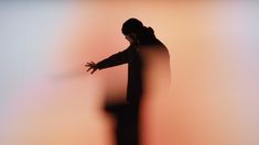 a blurry image of a man standing in front of a wall with his arms outstretched