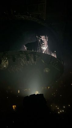 the stage is lit up at night with lights on it and an image of a man's face projected in the background