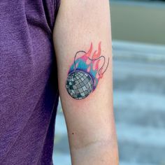 a woman's arm with a tattoo on it that has a disco ball in the middle