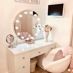 a white desk topped with a mirror next to a chair and vase filled with flowers