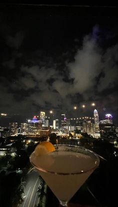 a martini sitting on top of a table in front of a city skyline