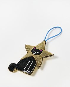 a black and white cat ornament hanging from a blue string on a white surface