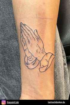 a tattoo on the wrist of a person holding their hands together