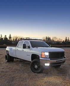 a white truck parked on top of a dry grass field