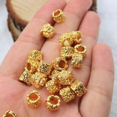 a person holding some gold beads in their hand