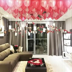 a living room filled with furniture and lots of balloons hanging from the ceiling above it