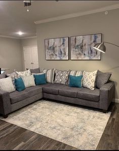 a living room with gray couches and blue pillows on the rug in front of it