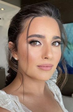 a woman in a white dress posing for the camera with her hair pulled back and eyes closed