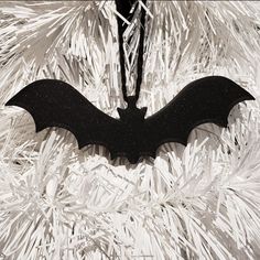 a bat ornament hanging on a white christmas tree in black and white colors