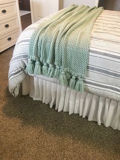 a bed with a blanket and pillows on top of it in a room that has carpeted flooring