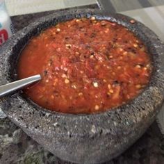 a bowl of chili with a spoon in it next to a can of soda on a table