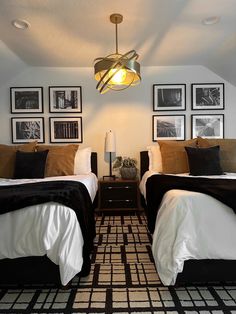 two beds in a room with pictures on the wall and lamps hanging from the ceiling