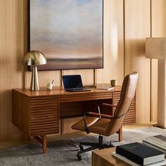 a desk with a laptop computer on top of it next to a chair and lamp