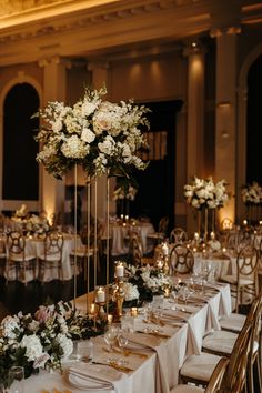 the tables are set with white flowers and gold place settings for an elegant wedding reception