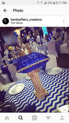 a blue and white table cloth with a gold crown on it, surrounded by chairs