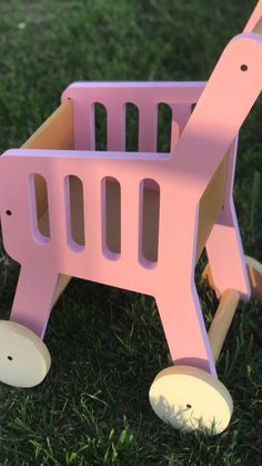 a pink toy horse with wheels in the grass