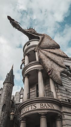 a giant dragon statue on top of a building next to a tall tower with a sign that says not's bank