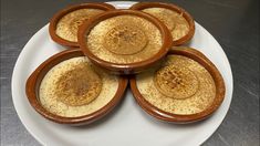 four brown bowls filled with food on top of a white plate