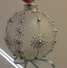 a hand holding a glass ornament with blue beads and silver trimmings