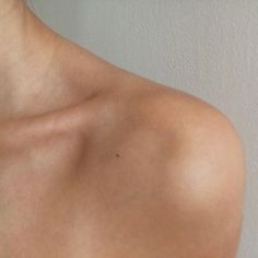 the back of a woman's shoulder with no shirt on, looking down at her neck