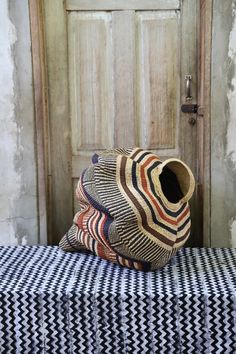 a basket sitting on top of a bed next to a wooden door