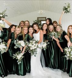 a group of women standing next to each other in green dresses holding bouquets and flowers