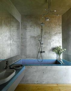 a bath room with a sink a mirror and a shower head mounted to the wall