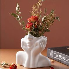 a vase with flowers in it sitting on a table next to a book and some books