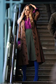 a woman walking down some stairs with her hand in her hair and wearing blue tights