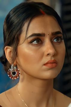 a close up of a woman wearing earrings and a necklace on her neck, looking off to the side