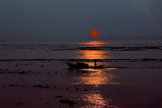 a small boat in the water at sunset